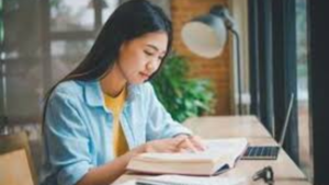 Student studying to score high in exams with study materials and a timetable.”